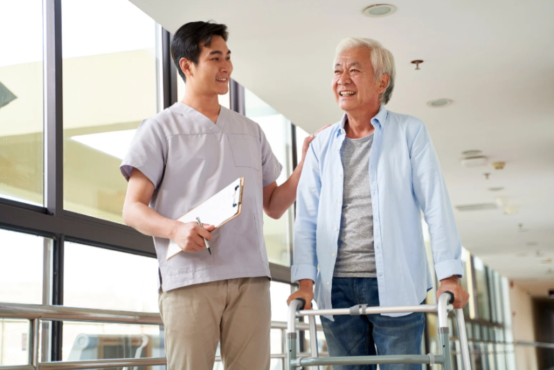 Physical therapist helping an elderly man exercise.