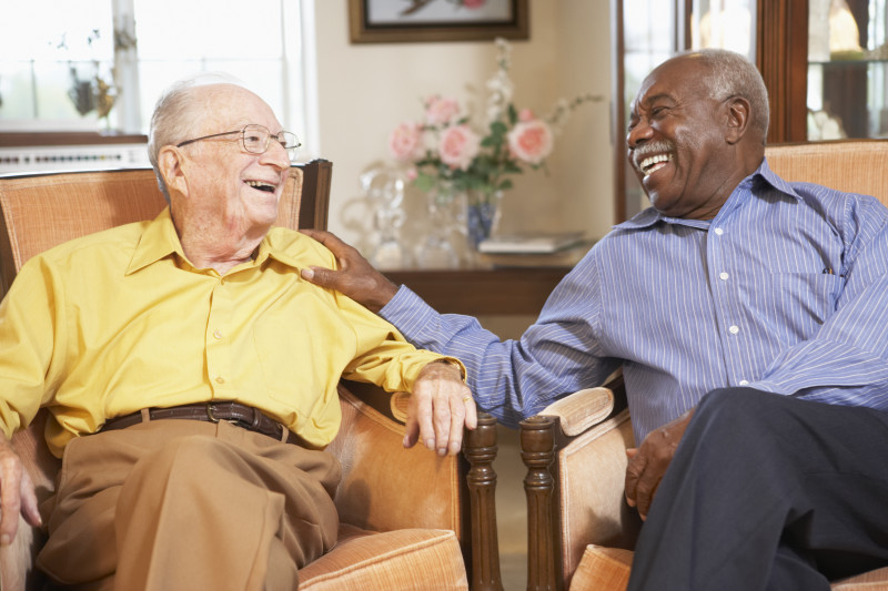 Two residents sitting next to one another and laughing.