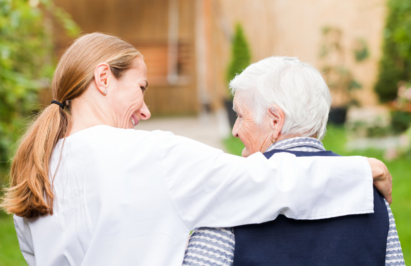 Nurse with her arm around the shoulders of a resident.
