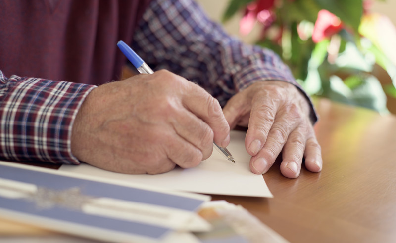 Resident holding a pen and writing.