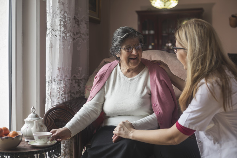 Nurse with her hand on a residents shoulder having a conversation.