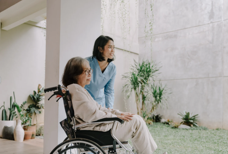 Nurse kneeling next to a resident in a wheelchair.