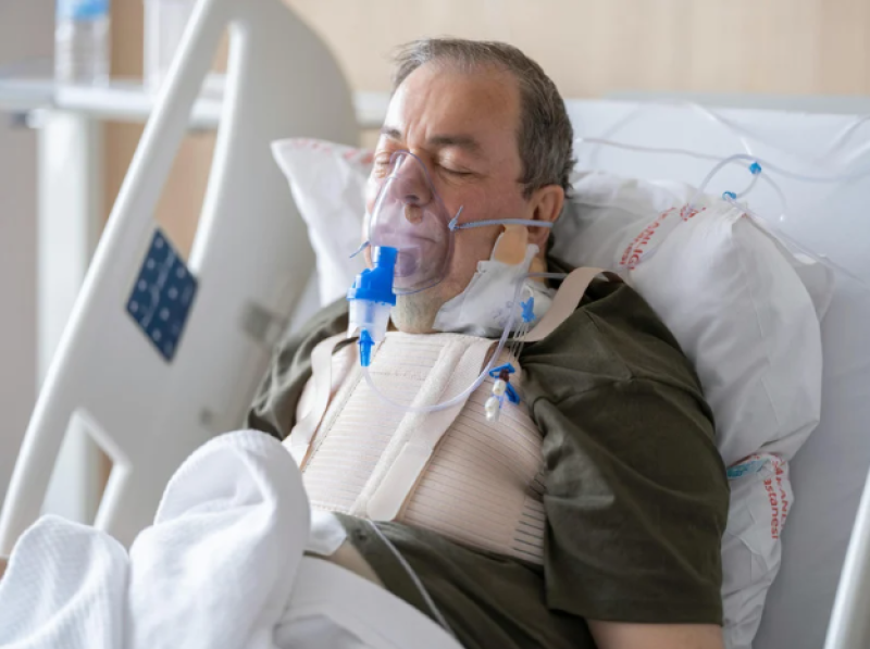 Patient sitting in a hospital bed wearing respiratory devices.